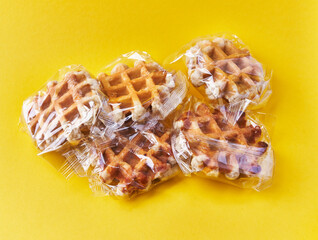  Bunch of delicious waffles wrapped on plastic bags over yellow background