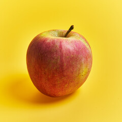 Single red apple fruit over yellow background