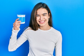 Young caucasian girl holding earwax cotton remover looking positive and happy standing and smiling with a confident smile showing teeth