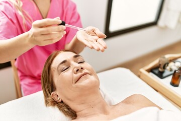 Obraz na płótnie Canvas Middle age caucasian woman having facial treatment at beauty center
