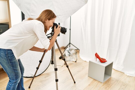 Middle age caucasian woman photographer make picture to high heel shoes at photograph studio