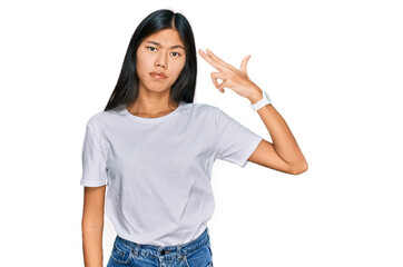 Obraz premium Beautiful young asian woman wearing casual white t shirt shooting and killing oneself pointing hand and fingers to head like gun, suicide gesture.
