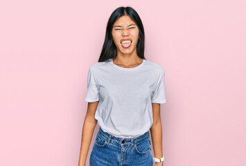 Beautiful young asian woman wearing casual white t shirt sticking tongue out happy with funny expression. emotion concept.