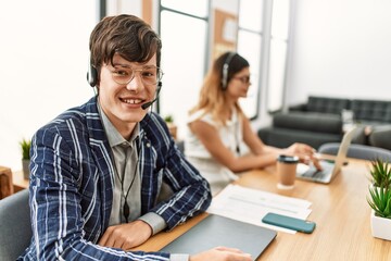 Two call center agents smiling happy working at the office.