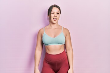 Young hispanic girl wearing sportswear winking looking at the camera with sexy expression, cheerful...
