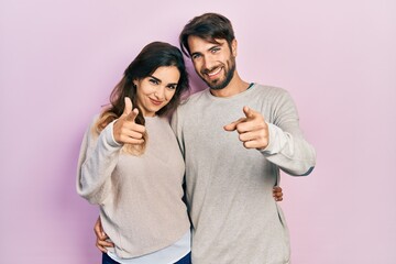 Naklejka premium Young hispanic couple wearing casual clothes pointing fingers to camera with happy and funny face. good energy and vibes.