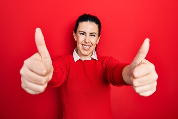 Young hispanic woman doing thumbs up positive gesture smiling with a happy and cool smile on face. showing teeth.