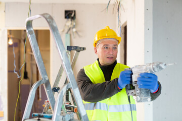 Confident male contractor holding electric perforator ready for construction works indoors