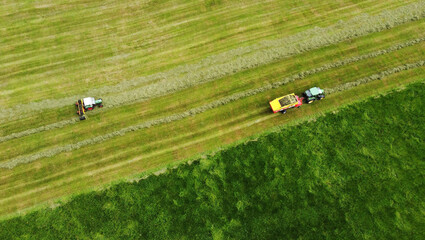 Luftaufnahme mit einer Drohne von zwei Traktoren bei der Heuernte auf einer Wiese in Bayern