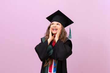 A joyful beautiful graduate looks up. a schoolgirl in a graduate's robe and a master's hat. the child is happy to receive an education in another country.