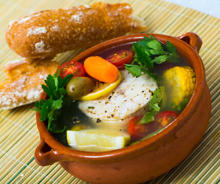 Fisher soup from merluccius. Recipe: boil broth from fish head, add potatoes, carrots, shallots, corn, fish fillets or steak 200 g, season with salt, pepper. Then cook in oven at 200 deg for 40min
