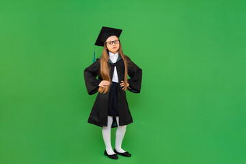 A full-length schoolgirl on an isolated green background in a master's robe and cap. the end of the academic year in a foreign school, admission to a higher education institution in another country.