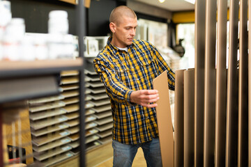American young man buyer choosing wooden panels for renovation at building store