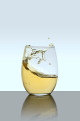 Glass cup with drink in motion with a white background