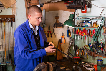 Portrait of qualified confident master of weapons working in workshop, repairing or renovating firearms .