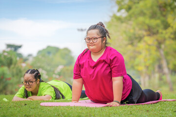 young woman with down syndrome or autism and friend doing yoga