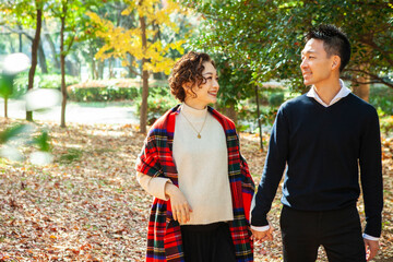 秋の公園を手を繋いで散歩する夫婦