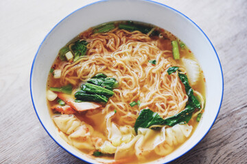 soup noodle wonton pork yellow noodle with red roasted pork dumpling and bog choy chinese vegetable in soup bowl on wooden table, top view