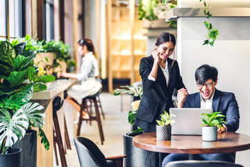 Group of asian business discussing meeting strategy sharing ideas thoughts with project.Creative business people working with laptop computer in green plant terrace decorated modern workloft