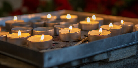 Burning prayer candles inside a catholic church. Lit tea lights. Selective focus.