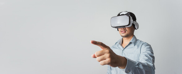 Excited young Asian wearing VR headset with hand pointing to space on web banner grey background.