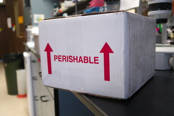 A white shipping box for temperature sensitive perishable products. Red arrows indicate this way up