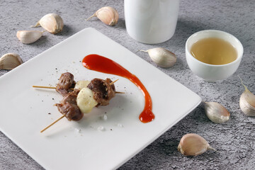 Chicken gizzard and grilled garlic skewers. Chicken gizzard and garlic served with alcoho