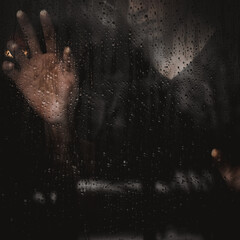 DRAMATIC IMAGE OF PERSON THROUGH WINDOW IN THE RAIN
