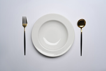 Spoon and fork near empty plate on white background. Healthy lifestyle concept.
