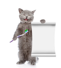 Happy kitten holds toothbrush and shows empty list. isolated on white background