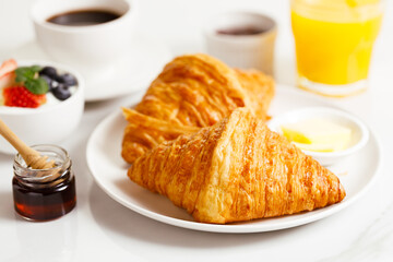 Breakfast with croissants, fresh berries yogurt and coffee on white table.