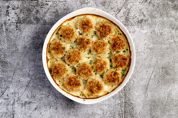 Meatballs with rice and meat with a cream sauce in a white baking dish on a dark grey background. Top view, flat lay