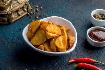 Deep-fried potato wedges with paprika and red sauce. Decorated in Asian style.