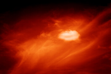 Red orange dramatic fiery sky with black clouds and yellow sunlight at sunset at night dusk before bad weather storm, fantastic scary anomalous natural background in horror style