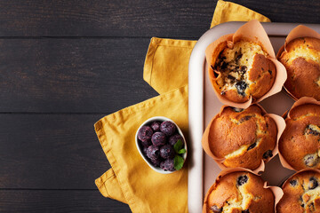 A group of mafins with berries and chocolate on a dark wooden background. FLat lay. Top view.