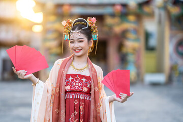 Asian Happy beauty little girl wearing Chinese ancient costumes holding red envelopes decoration...