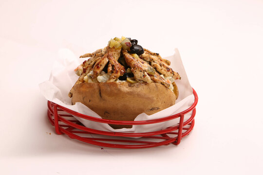Baked kumpir potato stuffed with the cheese, sausage, olives, peppers and corn