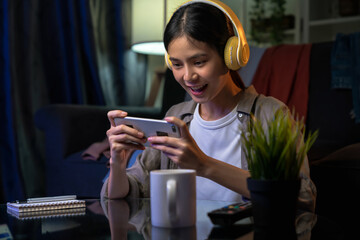 Excited Young Asian woman wearing headset and playing online game on smartphone with live broadcasting on internet. © sitthiphong