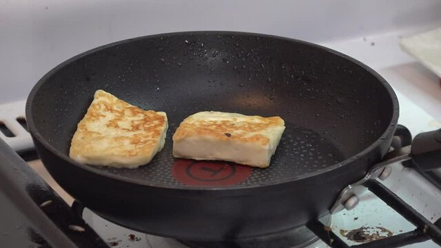 Frying cheese on a pot and flipping it with pincers