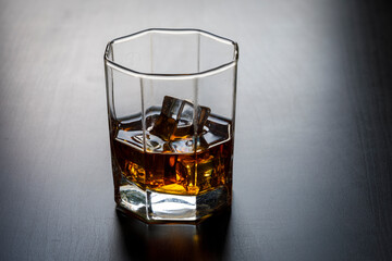 A glass of whiskey with ice cubes on the table close-up.