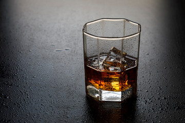 A glass of whiskey with ice cubes on the table close-up.