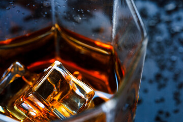 A glass of whiskey with ice cubes on the table close-up. Top view.