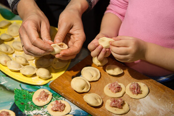 Mother and daughter cook homemade dumplings together in the kitchen.