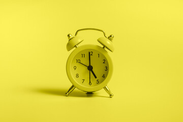 Yellow alarm clock with graduation cap on blue background closeup with copy space