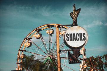 Aged and worn vintage photo of Ferris wheel at carnival with snacks sign