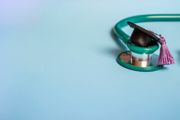 Graduation cap with stethoscope and numbers 2022 on blue background, closeup with copy space. Medical education concept.