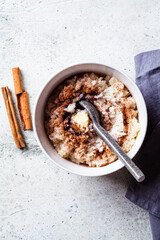 Scandinavian rice porridge with cinnamon and butter in white bowl on gray background. Norwegian cuisine concept.