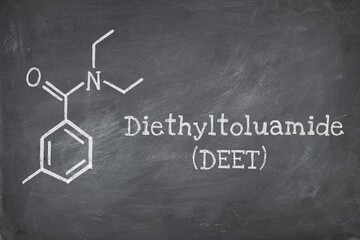 Chemical structure of diethyltoluamide (DEET), is an active ingredient in insect repellents. Blackboard background.