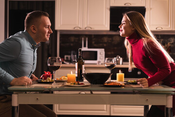 Happy young couple in love celebrate valentine's day, have dinner together, have a romantic candlelight dinner, sit at home table on valentine's day