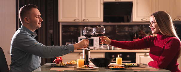 A couple in love on valentine's day have dinner at home and drink red wine in glasses. Alcohol at...
